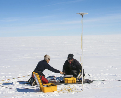 to personer sitter på snø med utstyr