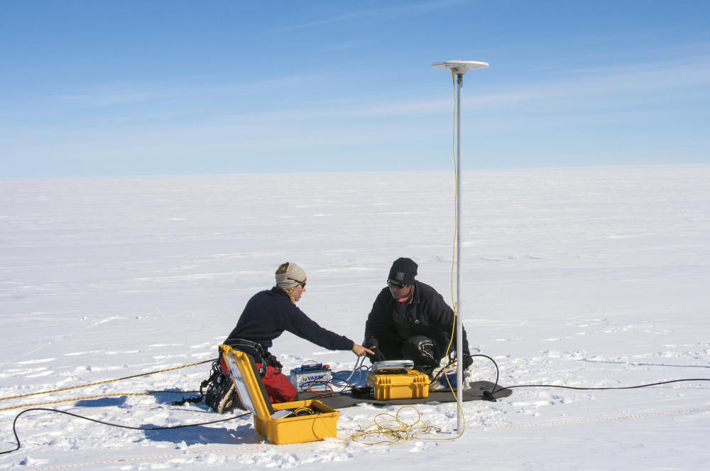 to personer sitter på snø med utstyr