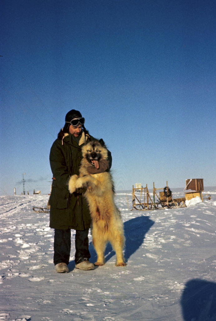 Mann i vinterklær koser med en polarhund som står på to ben