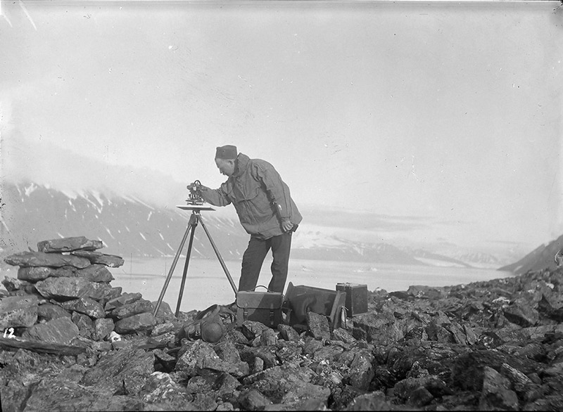 mann med måleapparat på tripod på fjell