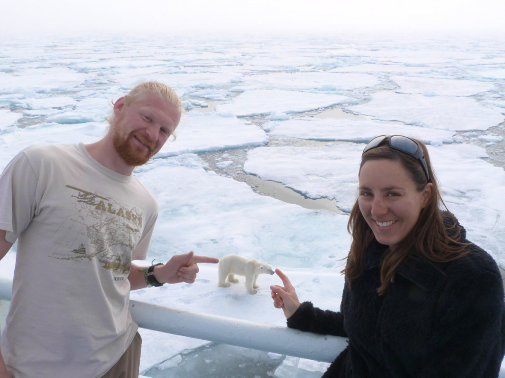Man and woman pointing at a polar bear from a ship