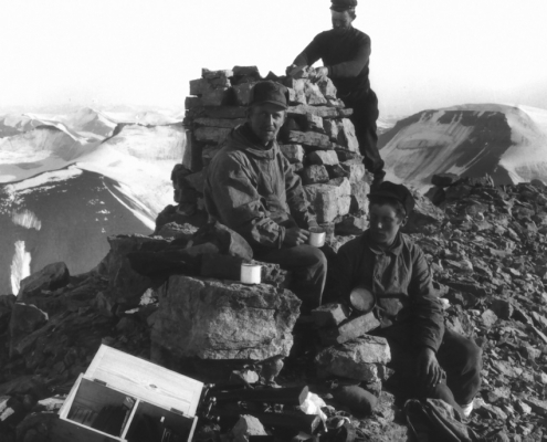 Tre menn tar en kaffepause ved en varde på et fjell