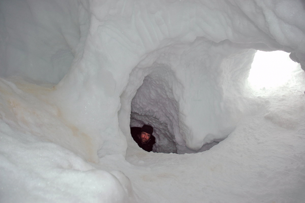 Man popping his head out from a snow den