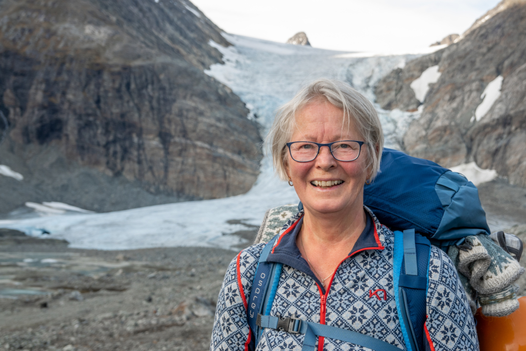 Kvinne med sekk står foran en isbre