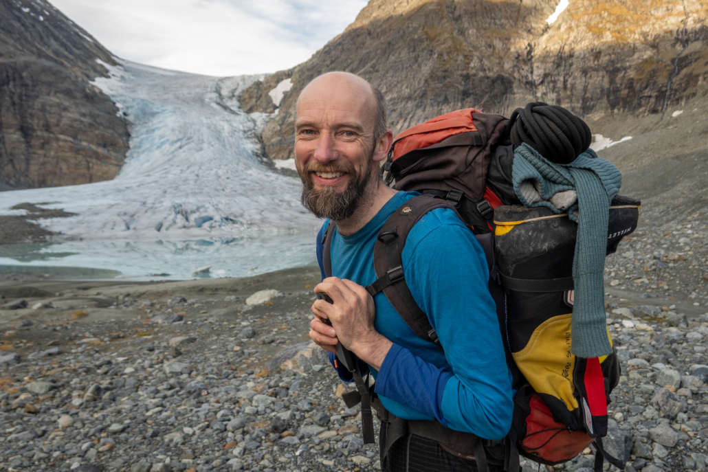 Mann med sekk på ryggen står foran en isbre