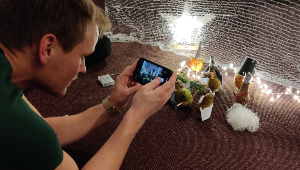 En person tar bilde av frukt på gulvet med mobilen sin