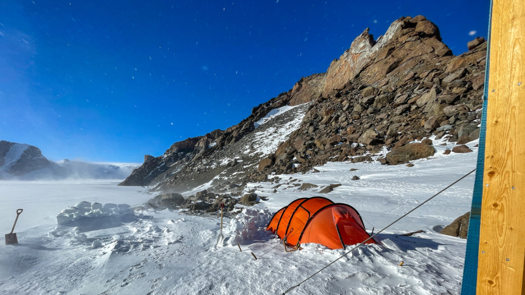Oransje telt på snø med fjell i bakgrunnen