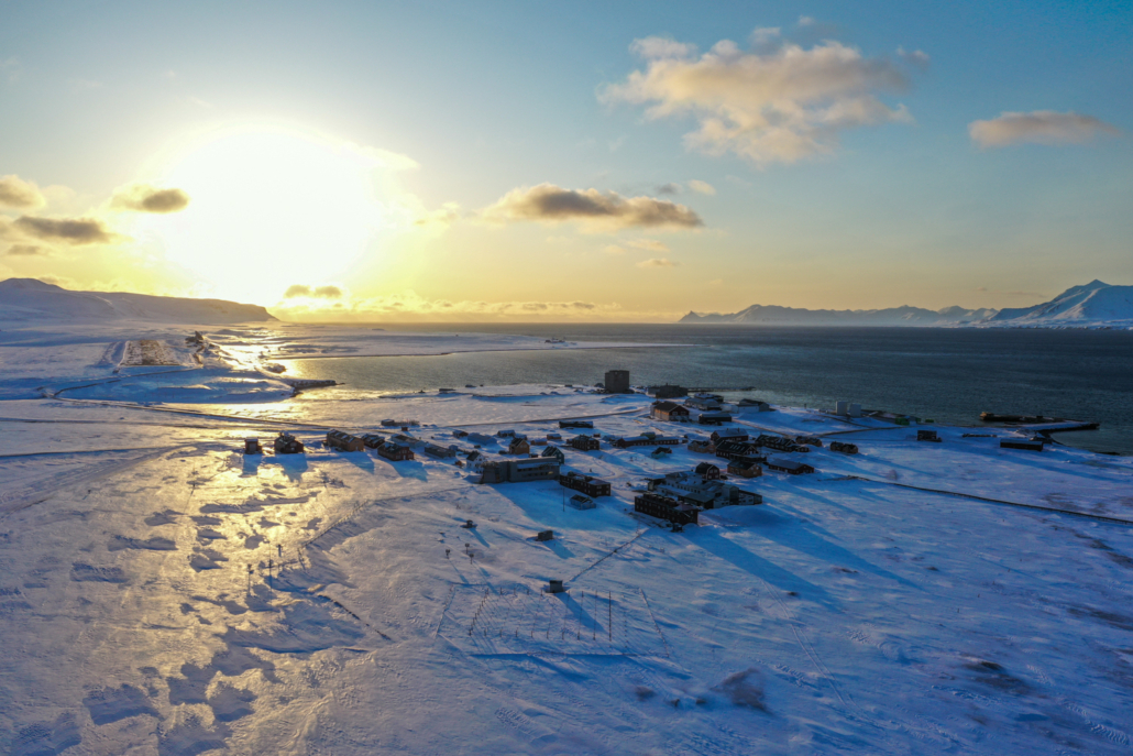 Bygninger ved en fjord. Snø på bakken