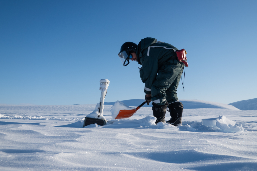 En person graver i snøen med en spade. Et instrument er nesten helt dekket av snø