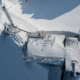 Bilde i fugleperspektiv over bygning dekket av sne med mast